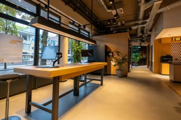 Moderne kantoorruimte aan de 1e Hogeweg met hoge werktafels, computers en strakke industriële afwerking.